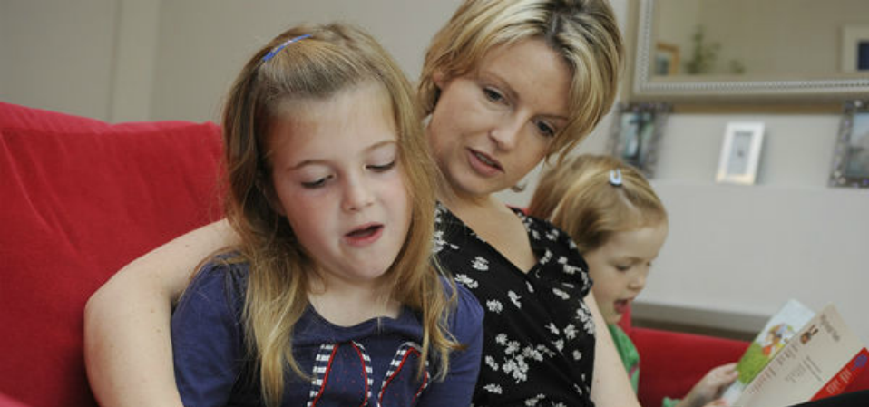 A mother reading a book to her two children