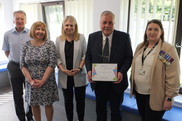 The Chief Medical Officer for Wales Sir Frank Atherton, Deputy Minister for Social Partnership Hannah Blythyn MS, Deputy Minister for Mental Health and Wellbeing Lynne Neagle MS, and Armed Forces Liaison Officer Lisa Rawlings present a certificate to Dr Chris Price.