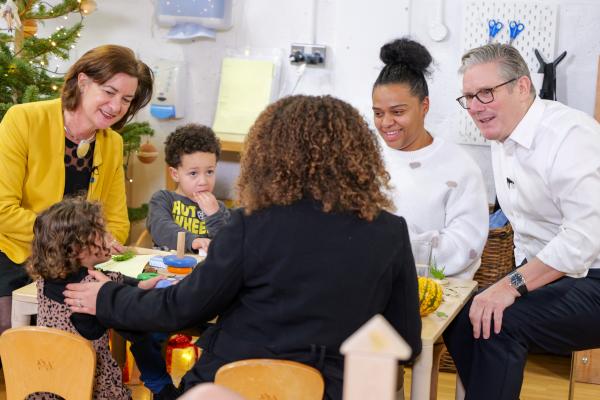 Wales' First Minister and the Prime Minister of Great Britain and Northern Ireland sitting with two small children and their mother, and a professional.