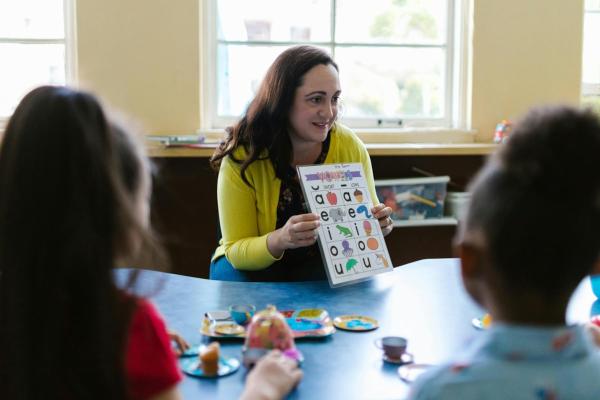 A teacher holding up an alphabet chart for learners.